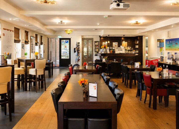 Gezellig ingerichte brasserie met houten tafels en rode en zwarte stoelen